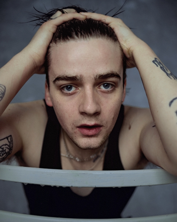 acting headshot of Louis Healy by London photographer Kim Hardy leaning on a chair and touching his hair