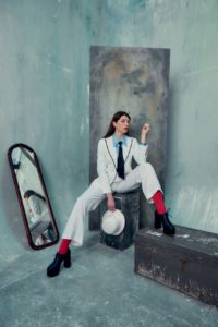 creative headshot of young actress wearing red socks and holding a white hat taken by photographer Kim Hardy in his London Studio in front of hand-painted backdrops