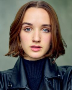 close up headshot of a young actor Kathryn Jennifer Jones wearing a black jacket black turtleneck taken by photographer Kim Hardy in his London studio in front of a light green background