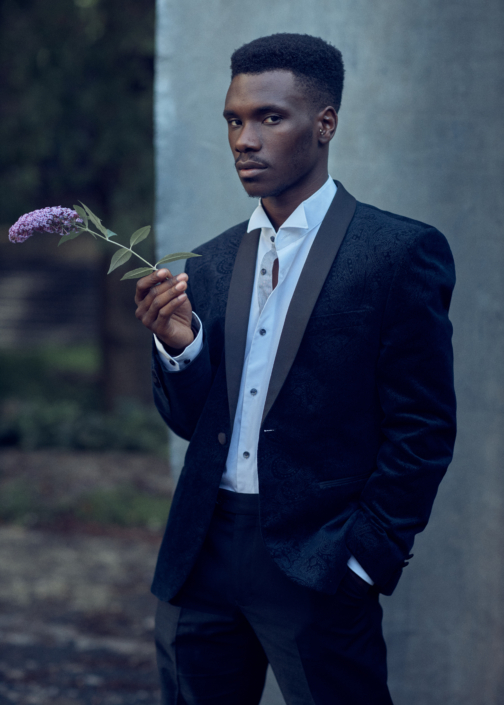 Professiona acting headshot of Michael Ahomka-Lindsay in an outside London location in front of a studio backdrop holding. flower taken by Kim Hardy