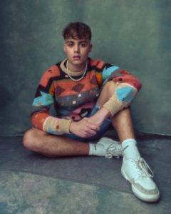 Headshot of actor Bradley Riches wearing colourful jumper taken by photographer Kim Hardy in his London studio in front of a hand-painted backdrop