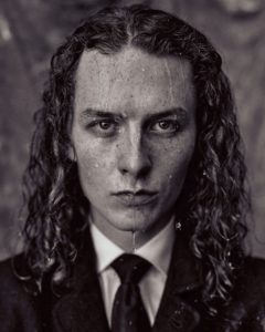 black and white headshot of Harry Kirton actor with long curly hair drenched in water taken by Kim Hardy in his London studio in front of a textured background