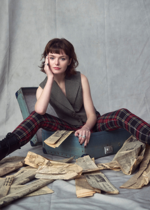 creative headshot of actor Sophie Bloor sitting in a suitcase filled with old newspapers taken by photographer Kim Hardy in his London studio location