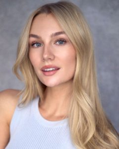 headshot of young blond actor with blue eyes wearing a white top taken by Kim Hardy in his London photography studio in front of a grey background