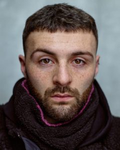 close-up headshot of a young freckled actor taken by Kim Hardy in his London studio in front of a grey background