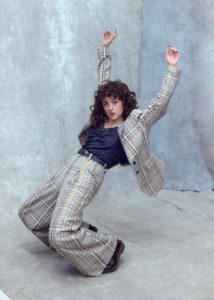 creative headshots of actor Eilidh Loan in a checked suit looking like she is falling over captured by photographer Kim Hardy in his London studio in front of a hand-painted cold backdrop