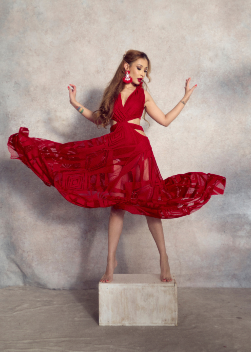 creative headshot of a young actor wearing red flowy dress in front of a grey background taken by photographer Kim Hardy in his London studio